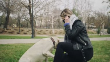 2019-2020 Coronavirus karantinasında karantina Coronavirus COVID-19 salgını sırasında kadın labrador köpeğiyle parkta oynuyor.