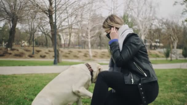 Žena si hraje se svým labradorským psem v parku během karantény koronaviru COVID-19 pandemie v letech 2019-2020 koronavirová karanténa — Stock video