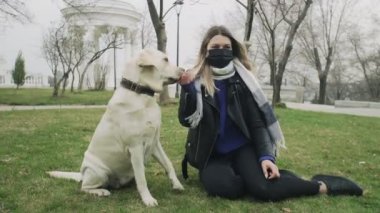 Kadın karantina Coronavirus COVID-19 salgını sırasında labrador köpeğiyle parkta oynuyor.