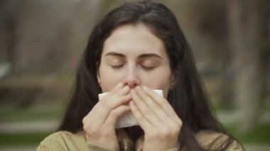 Açık havada öksüren genç bir kadının portresi.