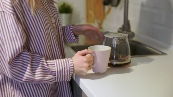 Close-up van jonge vrouw schenkt en drinkt koffie thuis in de keuken — Stockvideo