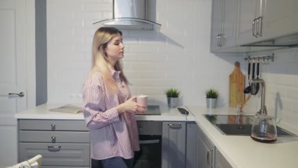 Mujer joven vierte y bebe café en casa en la cocina — Vídeos de Stock