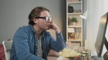 Video oyunu oynayan ve monitörün önünde oturan konsantre genç adamın yan görüntüsü