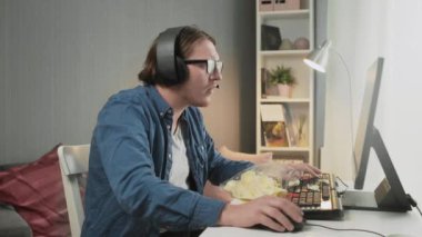 Evde video oyunu oynayan genç bir adamın, kaybettikten ve uygunsuz davranışlar sergiledikten sonra üzgün görünümü