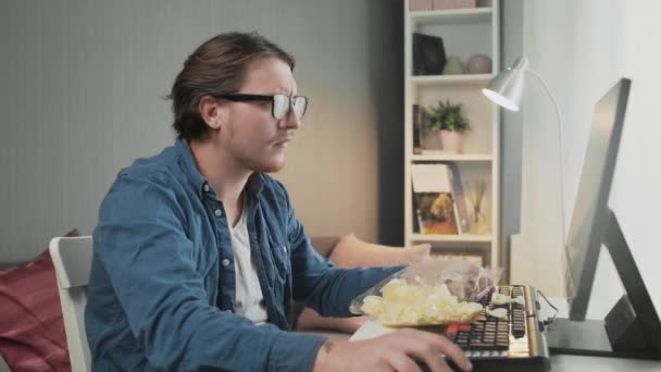 Вид сбоку молодого человека, играющего в видеоигру и сидящего перед монитором — стоковое видео