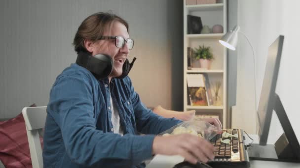 Boční pohled na Mladý muž hraje videohry doma pocit štěstí po vítězi a ukazuje neslušné gesto — Stock video