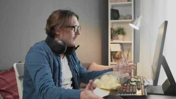 Divertente giovane uomo in cuffia con pc computer gioco a casa. — Video Stock