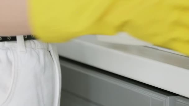 Kobieta w żółtych rękawiczkach umyć stół żółtą szmatą i detergentem. — Wideo stockowe