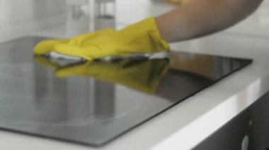 Mutfaktaki tencere kapağını yağlı temizleme spreyi ve sarı lastik eldivenli bir kadının beyaz paçavrasıyla temizliyorum..