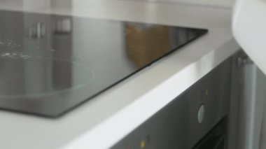 Mutfakta, sarı lastik eldivenli bir kadın tarafından yağlı temizleme spreyi ve sarı paçavrayla temizleniyor..