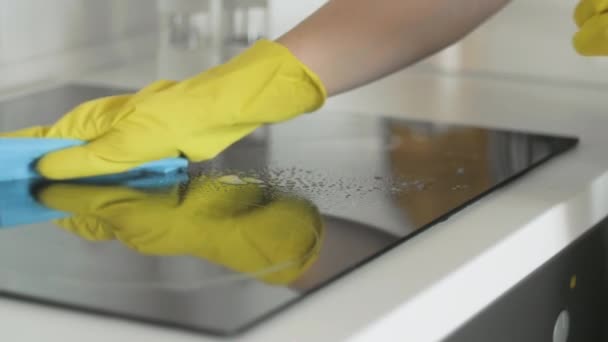 Panneau de cuisson de table de cuisson de nettoyage dans la cuisine avec spray dégraissant et chiffon bleu par une femme en gants de caoutchouc jaune . — Video