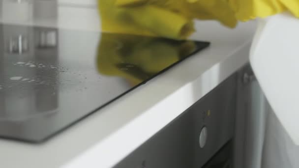Πίνακας μαγειρέματος βάσης εστιών καθαρισμού στην κουζίνα με σπρέι αφαίρεσης λίπους και κίτρινο πανί από μια γυναίκα με κίτρινα λαστιχένια γάντια. — Αρχείο Βίντεο