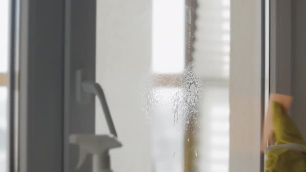 Casalinga in guanti gialli lavare le finestre con straccio arancione e detergente . — Video Stock