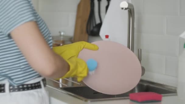 Kvinnliga händer sköljer tallriken vid diskhon - gör sysslorna hemma med tvättmedel. Diskrutin, statisk kamera. — Stockvideo