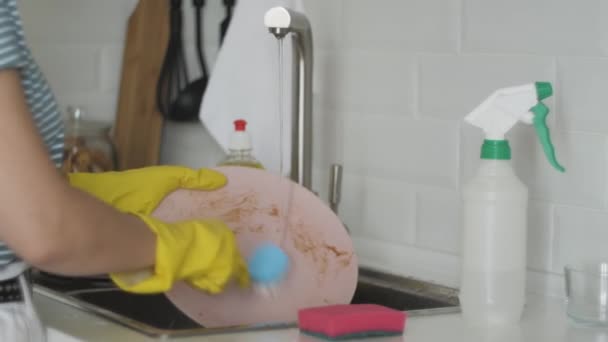 Жінка миє брудний посуд в мийці на кухні — стокове відео