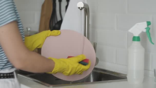 Young woman with gloves washing dishes in the kitchen — Stock Video