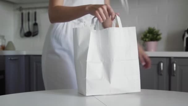 Primer plano de la mujer joven desembalaje bolsa de compras de papel con frutas en la cocina en la mesa de madera. Residuos cero hogar y bolsa ecológica. Eco Shopping . — Vídeos de Stock