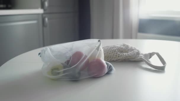 Alacsony hulladék életmód. Újrahasznosítható hálós zsákok friss zöldségekkel a konyhaasztalon — Stock videók