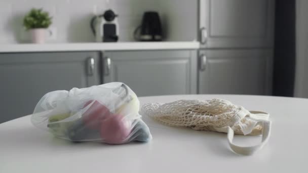 Dolly movimento de malha reutilizável produzir sacos com legumes frescos na mesa da cozinha — Vídeo de Stock