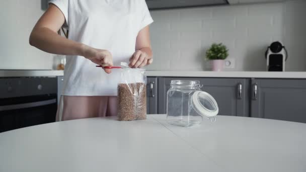 La donna versa il grano saraceno in un vaso di vetro per immagazzinamento . — Video Stock