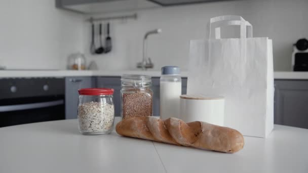 Bolsa de compras sin envasar con pan, avena, trigo sarraceno, leche, verduras en mesa de madera en la cocina. Residuos cero hogar y bolsa ecológica. Eco Shopping . — Vídeo de stock