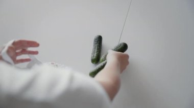 Mutfaktaki ahşap masanın üstünde salatalık, domates ve biberli alışveriş torbalarını açan kadının omuz manzarası. Sıfır atık ev ve çevre torbası. Çevre Alışverişi.