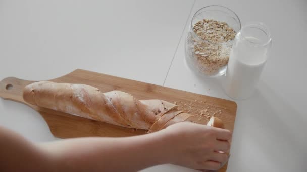 Jonge vrouw eet gesneden brood en drinkt melk — Stockvideo