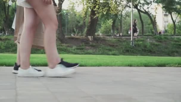 Fiatal szép pár sétál a nyári parkban bevásárlótáskákkal a kezében — Stock videók