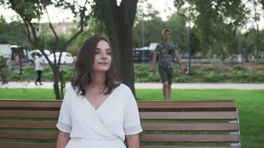 Genç kadın bankta oturuyor ve yaz parkında erkek arkadaşını bekliyor.