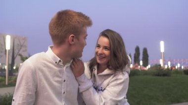 Genç ve sevimli bir çift akşamları yaz parkında oturup sohbet eder.