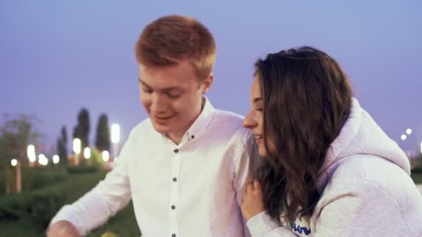 Young lovely couple sits and talks in the summer park in the evening — Stock Video