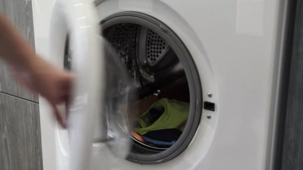 Female hand takes clothes from laundry machine. Loading washing machine. Load clothes to washer machine. Load clothes laundry washing machine. Preparing laundry washing — Stock Video