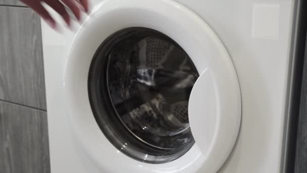 Female hand put WHITE TOWEL in laundry machine. Loading washing machine. Load clothes to washer machine. Load clothes laundry washing machine. Preparing laundry washing — Stock Video