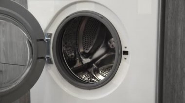 Evlilik yüzüklü kadın eli, çamaşır makinesine koyuyor. Çamaşır makinesi yükleniyor. Giysileri çamaşır makinesine yükleyin. Çamaşır makinesini yükle. Çamaşır yıkıyorum.