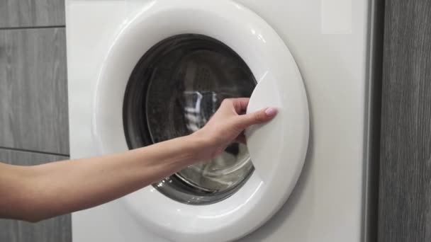 Female hand with married ring takes WHITE CLOTHES from laundry machine. Loading washing machine. Load clothes to washer machine. Load clothes laundry washing machine. Preparing laundry washing — Stock Video