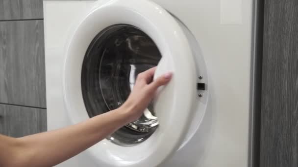 Mano femenina con anillo de casado poner ROPA BLANCA en la lavadora. Cargando lavadora. Carga la ropa a la lavadora. Carga la ropa lavadora. Preparación del lavado de ropa — Vídeos de Stock