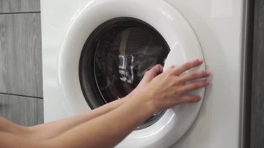 Kadın eli çamaşır makinesinden soğuk giysiler alıyor. - Ne? Çamaşır makinesi yükleniyor. Giysileri çamaşır makinesine yükleyin. Çamaşır makinesini yükle. Çamaşır yıkıyorum.