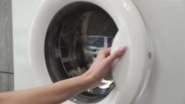 Mano femenina con anillo de casada poner SNEAKERS VERDE en la lavadora. Cargando lavadora. Carga la ropa a la lavadora. Carga la ropa lavadora. Preparación del lavado de ropa — Vídeos de Stock