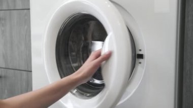 Evlilik yüzüklü bir kadın çamaşır makinesinden COLORED giysiler alır. Çamaşır makinesi yükleniyor. Giysileri çamaşır makinesine yükleyin. Çamaşır makinesini yükle. Çamaşır yıkıyorum.