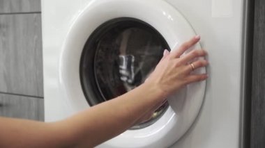 Evlilik yüzüklü bir kadın çamaşır makinesinden COLORED giysiler alır. Çamaşır makinesi yükleniyor. Giysileri çamaşır makinesine yükleyin. Çamaşır makinesini yükle. Çamaşır yıkıyorum.