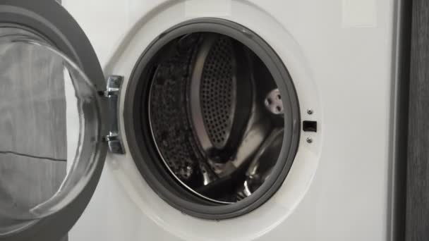 Vrouwelijke hand zet WHITE SWEATER in de wasmachine. Laden wasmachine. Laad kleren in de wasmachine. Laad kleding wasmachine. Wasgoed klaarmaken — Stockvideo