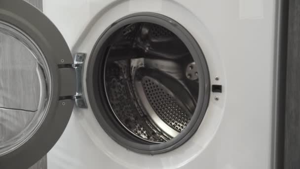 Female hand puts BLACK CLOTHES in laundry machine. Loading washing machine. Load clothes to washer machine. Load clothes laundry washing machine. Preparing laundry washing — Stock Video