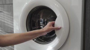 Kadın eli, çamaşır makinesinden siyah giysileri alıyor. Çamaşır makinesi yükleniyor. Giysileri çamaşır makinesine yükleyin. Çamaşır makinesini yükle. Çamaşır yıkıyorum.