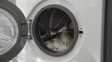 Evlilik yüzüklü bir erkek çamaşır makinesinden beyaz giysiler alır. Çamaşır makinesi yükleniyor. Giysileri çamaşır makinesine yükleyin. Çamaşır makinesini yükle. Çamaşır yıkıyorum.