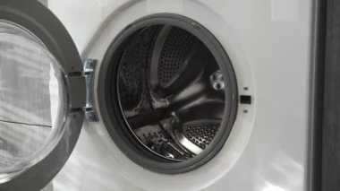 Evlilik yüzüklü bir erkek çamaşır makinesine beyaz giysiler koyar. Çamaşır makinesi yükleniyor. Giysileri çamaşır makinesine yükleyin. Çamaşır makinesini yükle. Çamaşır yıkıyorum.