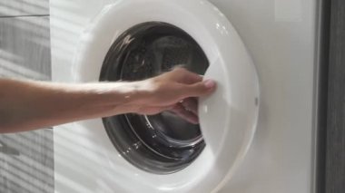Evlilik yüzüklü bir erkek çamaşır makinesinden soğuk giysiler alır. Çamaşır makinesi yükleniyor. Giysileri çamaşır makinesine yükleyin. Çamaşır makinesini yükle. Çamaşır yıkıyorum.
