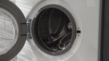 Evlilik yüzüklü bir erkek çamaşır makinesine soğuk giysiler koyar. Çamaşır makinesi yükleniyor. Giysileri çamaşır makinesine yükleyin. Çamaşır makinesini yükle. Çamaşır yıkıyorum.