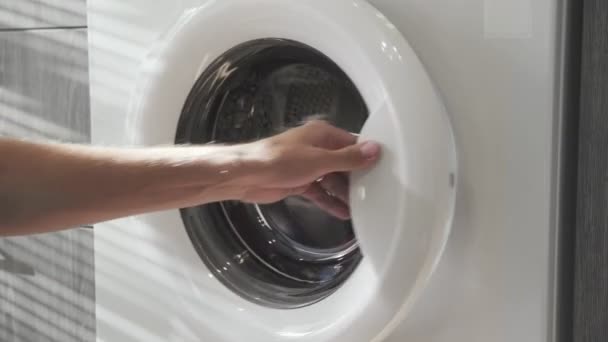 Mão masculina com anel casado leva CLOTHES coloridos da máquina de lavar roupa. Carregando máquina de lavar roupa. Carregue roupas para a máquina de lavar. Carregar roupa máquina de lavar roupa. Preparação de lavagem de roupa — Vídeo de Stock