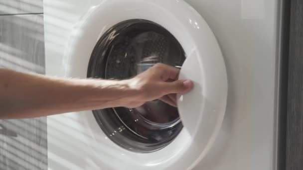 Mano masculina con anillo de casado toma ROPA COLORADA de la lavadora. Cargando lavadora. Carga la ropa a la lavadora. Carga la ropa lavadora. Preparación del lavado de ropa — Vídeos de Stock