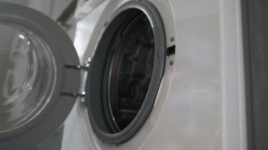 Evlilik yüzüklü kadın eli, çamaşır makinesindeki Pink CLOTHES 'i koyuyor. Çamaşır makinesi yükleniyor. Giysileri çamaşır makinesine yükleyin. Çamaşır makinesini yükle. Çamaşır yıkıyorum.